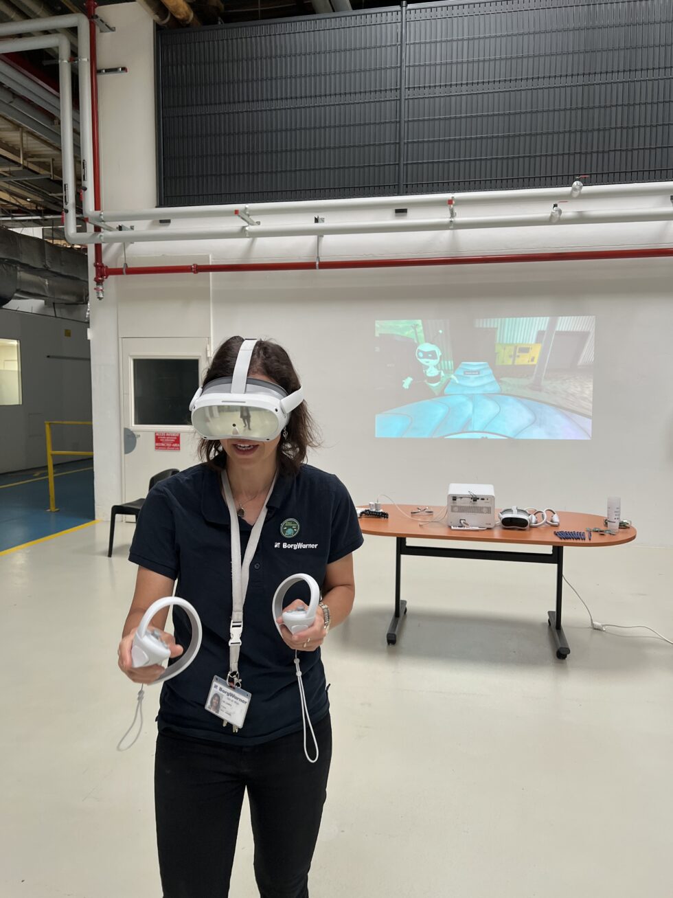 Une personne utilise un casque et deux contrôleurs VR devant une projection murale de l’expérience.